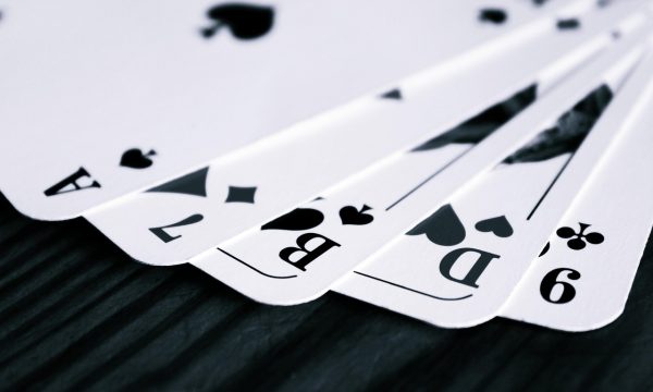 深色桌面上整齐摆放的扑克牌，黑桃A朝上，冷蓝灯光打出专业牌局氛围